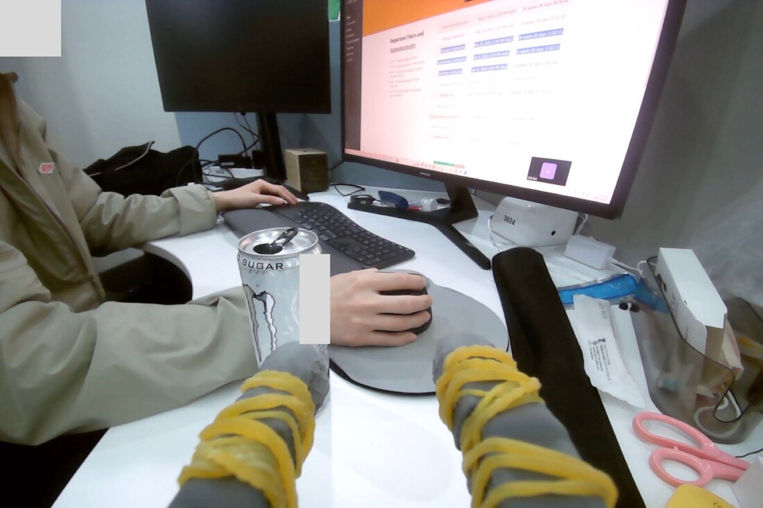 First-person SO-101 arm view of a desk where a person is working